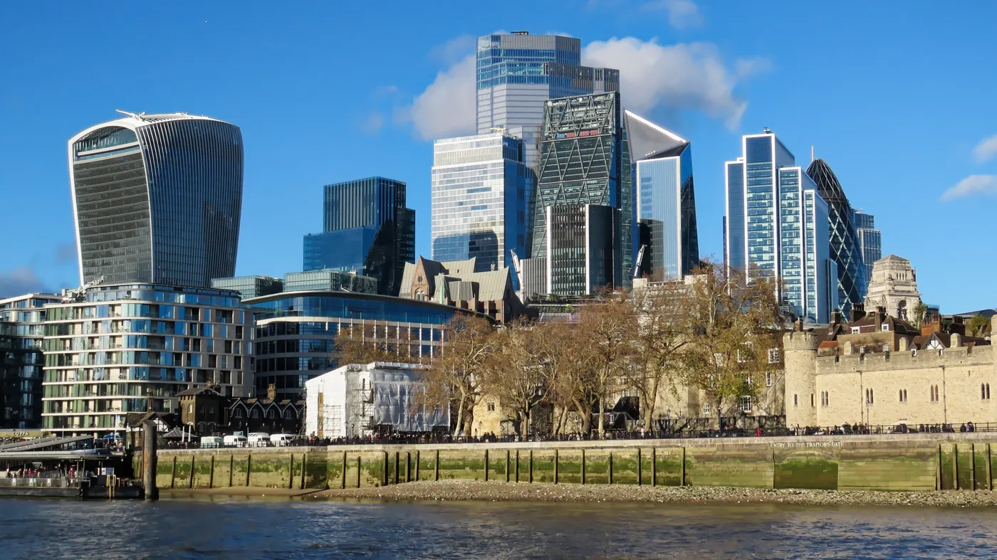 The Tower of London on the riverbank with the modern towers of the City of London rising behind it