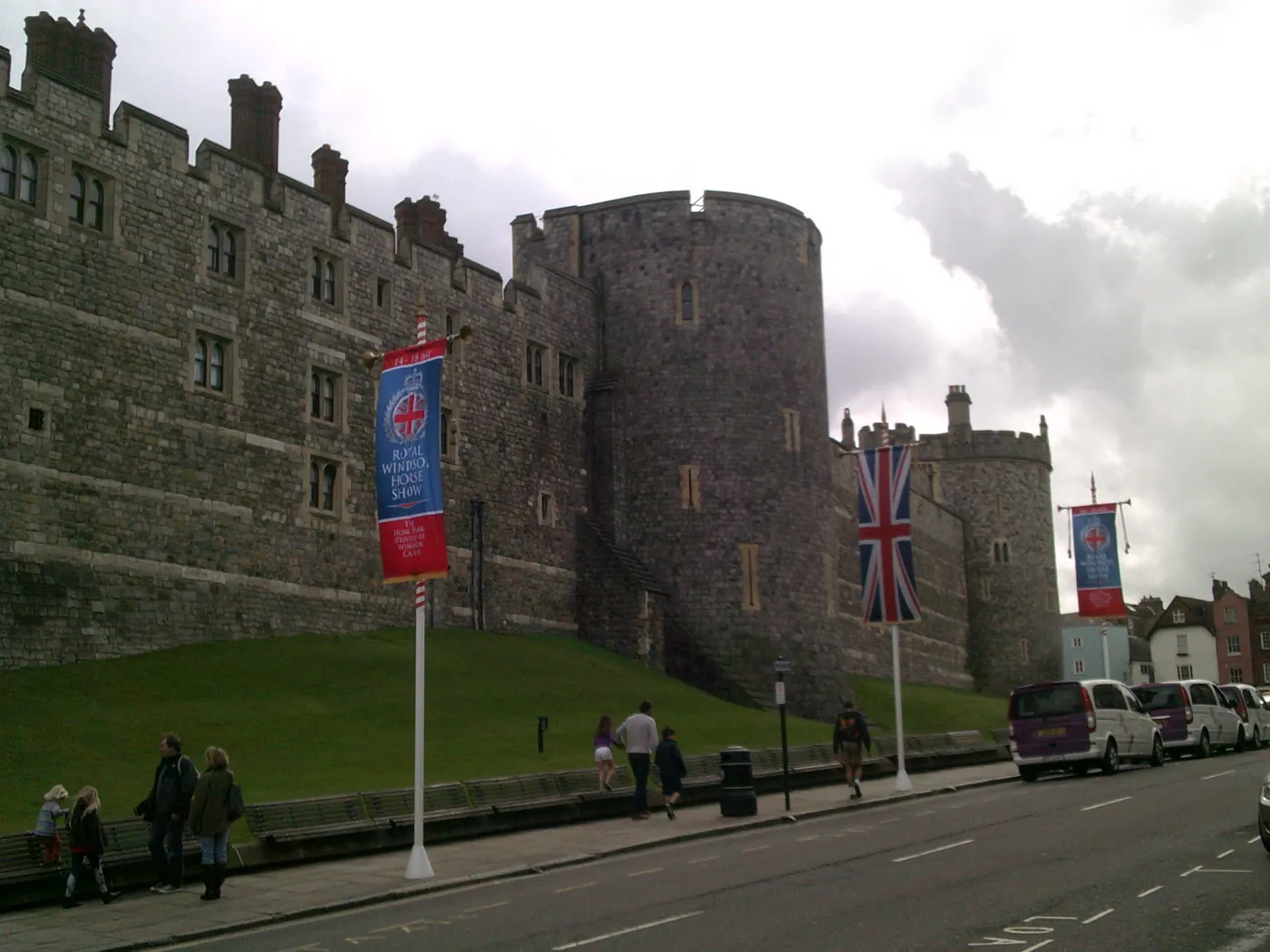 Stone curtain walls and round towers of Windsor Castle above a lawn on Castle Hill